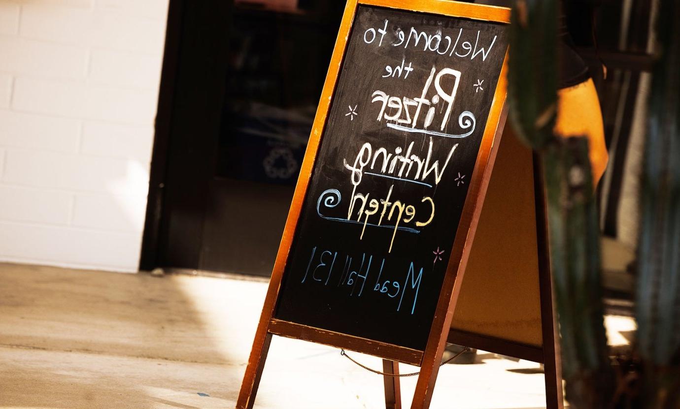 a sandwich board outside the writing center with the words "welcome to the writing center" Meal hall 131