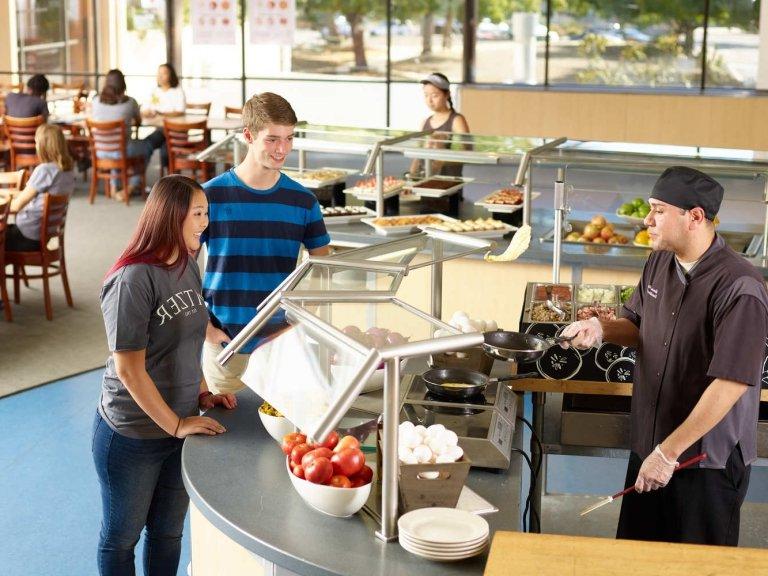 Pitzer students watch a dining services chef flip an omlette in McConnell